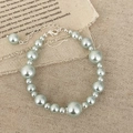 Elegante pulsera de perlas con cierre de mosquetón plateado y extensión sobre fondo rústico - Pulsera de perlas azul glaciar / Azul glaciar