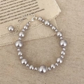 Elegante pulsera de perlas plateadas con cierre de mosquetón sobre fondo de lino - Pulsera Manta Rosa / Púrpura Grisáceo