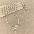 Dettaglio della collana di perline con perla, cuore rosa e fiocco su carta vintage - Collana a Fiocco Argento