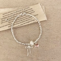 Dettaglio di bracciale in argento con perla, ciondolo a cuore e fiocco su tessuto lino - Bracciale con Fiocco Argento
