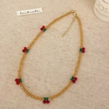 Collier artisanal en perles ambrées avec breloques cerises sur un fond de lin naturel - Collier Jaune