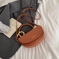 Sacoche selle marron mat avec anneau doré et bandoulière fine sur un costume gris - Marron