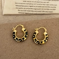 Detailaufnahme der Vintage-Goldohrringe mit Leoparden-Emaille auf Retro-Hintergrund - Goldene Ohrringe Mit Luipaardmuster Und Öltropfen