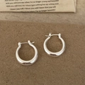 Eleganti orecchini a cerchio in argento lucido a specchio su sfondo vintage caldo - Orecchini a Cerchio Argentati Lucidi