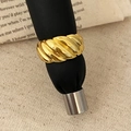 Makroaufnahme eines goldenen Croissant-Rings auf schwarzem Lederständer mit Stoffhintergrund - Gold