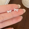 Exquisite silver bow stud earrings in a minimalist 3D design shown on finger - Silver Bow Stud Earrings (A-38)