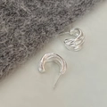 Macro detail of silver layered C-shaped stud earrings with textured metallic finish - Silver