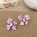 Vue macro de boucles d'oreilles fleurs mauves avec perles et bords argentés sur papier - Violet