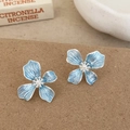 Close-up of light blue flower stud earrings with central pearl and silver metallic texture - Blue