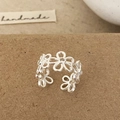 Anillo abierto de plata minimalista con diseños de margaritas huecas sobre papel marrón - Anillo hueco plateado
