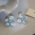 Détail de boucles d'oreilles fleurs bleu clair avec perles fines sur tissu lin - Bleu