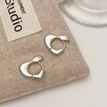 Close-up of heart-shaped silver earrings on canvas texture, showing shiny metallic finish - Heart Ear Clips (A-878)