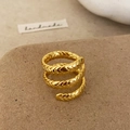 Detailed close-up of golden spiral ring with intricate braided texture and polished finish - Gold
