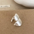 Detalle de un ear cuff de plata mate con acabado cepillado sobre un fondo texturizado - Ear Cuff de Plata Cepillado