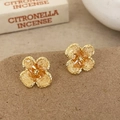 Detalle de pendientes de flores de cuatro pétalos en oro y ámbar sobre superficie rugosa - Ámbar (Beige)