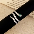 Macro detail of silver snake ring with white pavé zircons and green gemstone eyes - Silver