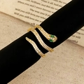 Macro shot of gold snake ring with white pavé zircons and green gemstone eyes - Gold