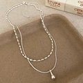 Close-up of double-layer silver teardrop pendant necklace on rustic ceramic tray - Silver Double Layer Teardrop