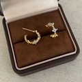 Macro shot of gold C-shaped earrings with blue floral stones in a velvet box - Gold Blue Zirconia Flower Studs