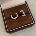 Macro view of C-shaped silver earrings with blue zircon stones on dark velvet - Silver Blue Zirconia Flower Studs