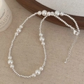 Dettaglio di elegante collana di perle con perline argentate e chiusura a moschettone - Collana di perle bianche