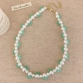 Detail of handmade pearl necklace with green beads and gold lobster clasp on linen - Green Crystal Wave Woven Style