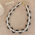 Detailed shot of wave-pattern pearl and black bead necklace with golden lobster clasp - Black Crystal Wave Woven Style