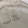 Détail d'un collier en argent avec six perles mates sur un plateau en verre - Style Perle en Cuivre Œil de Chat Argenté