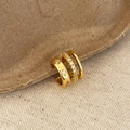 Detail van een gouden gelaagde ear cuff met getextureerde band en zirkonia pavé-zetting - Gouden meerlaagse zirkonia oormanchet