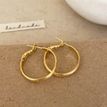 Detailed shot of gold hammered round hoop earrings on a vintage paper background - Gold 2.5cm