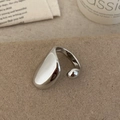 Macro detail of a minimalist silver organic drip ring on a rustic textured surface - Shiny Silver Ring