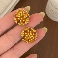 Detail of vintage gold flower cluster earrings held against a cozy candlelit background - Matte Gold Flower Cluster Stud Earrings