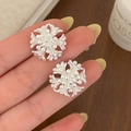 Elegant matte silver floral earrings with multi-layered petals in a hand-held display - Matte Silver Flower Cluster Stud Earrings