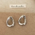 Macro-opname van zilveren druppeloorbellen met een hoogglans afwerking op handmade label - Zilver