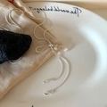 Detailansicht der silbernen Schleifen-Halskette mit langen Quasten und Tropfenanhängern - Silber Schleife Quaste Stil