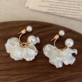 Detalle de pendientes de pétalos con perlas sobre bandeja de madera y lino beige - Pendientes de botón de perlas doradas y pétalos