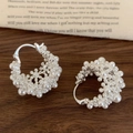 Detail of elegant silver hoop earrings with clustered white pearls on a rustic background - Silver