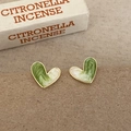 Primer plano de pendientes de esmalte verde con forma de corazón y textura jaspeada - Pendientes de botón de corazón de esmalte verde y blanco