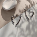 Detail showing polished silver heart stud earrings with elegant leaf shadows on a minimal base - Silver