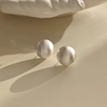 Macro detail of round brushed silver earrings featuring textured finish and artistic shadows - Brushed Silver