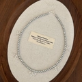 Detailansicht der Perlenkette mit fünf eleganten silbernen Schleifenanhängern auf Tablett - Graue Perle Silberne Schleife Halskette