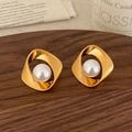 Detail of twisted Mobius gold earrings with lustrous pearls on a walnut tray - Gold