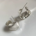 Dettaglio di orecchini a C in argento con una finitura metallica a specchio lucida - Argento