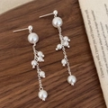 Detail of silver long tassel earrings with lustrous pearls on a wooden surface - Silver High Luster Pearl Tassel Stud Earrings