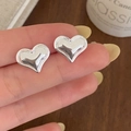 Close-up of minimalist heart stud earrings in polished silver finish held by hand - Silver Heart Stud Earrings