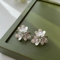 Close-up of elegant flower stud earrings with zircon centers on a dark green tray - Silver Floral Stud Earrings