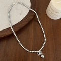 Detalle de collar de perlas con lazo plateado sobre una elegante superficie de tela - Collar de Perlas Grises con Lazo Plateado (B-79)