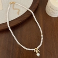 Detalle de collar de perlas francesas con colgante de lazo dorado y cierre ajustable - Collar de Perlas Blancas con Lazo Dorado (B-79)