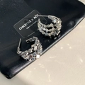 Détail macro de boucles d'oreilles géométriques en argent avec texture métallique polie - Argenté