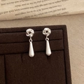 Detailed view of silver knot earrings with frosted teardrop tassels on velvet display - Silver